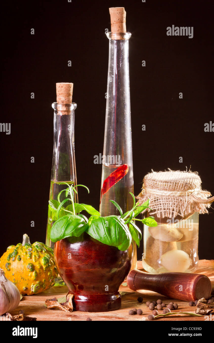 Flasche mit pflanzlichen Ölen und frischen Gewürzen in Holzregal Stockfoto