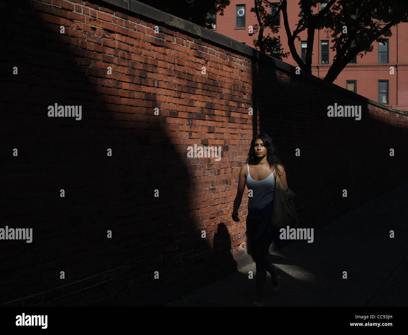 New York City-Licht und Schatten, geht Frau vorbei an katholische Kirche Wand in Little Italy Bereich Stockfoto