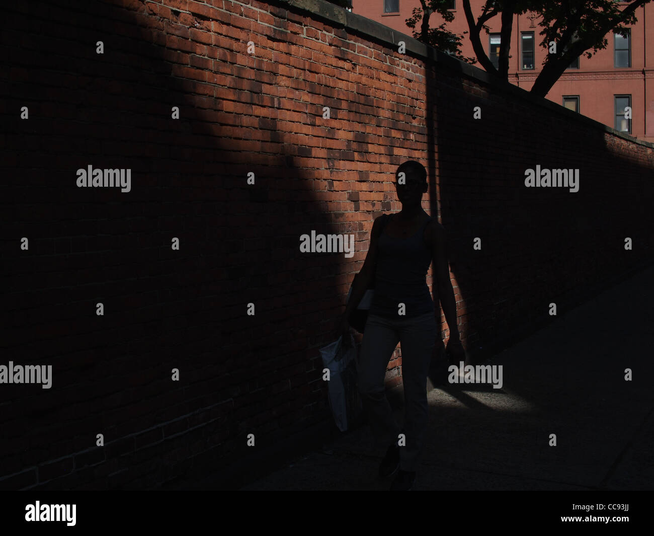 New York City-Licht und Schatten, geht Frau vorbei an katholische Kirche Wand in Little Italy Bereich Stockfoto