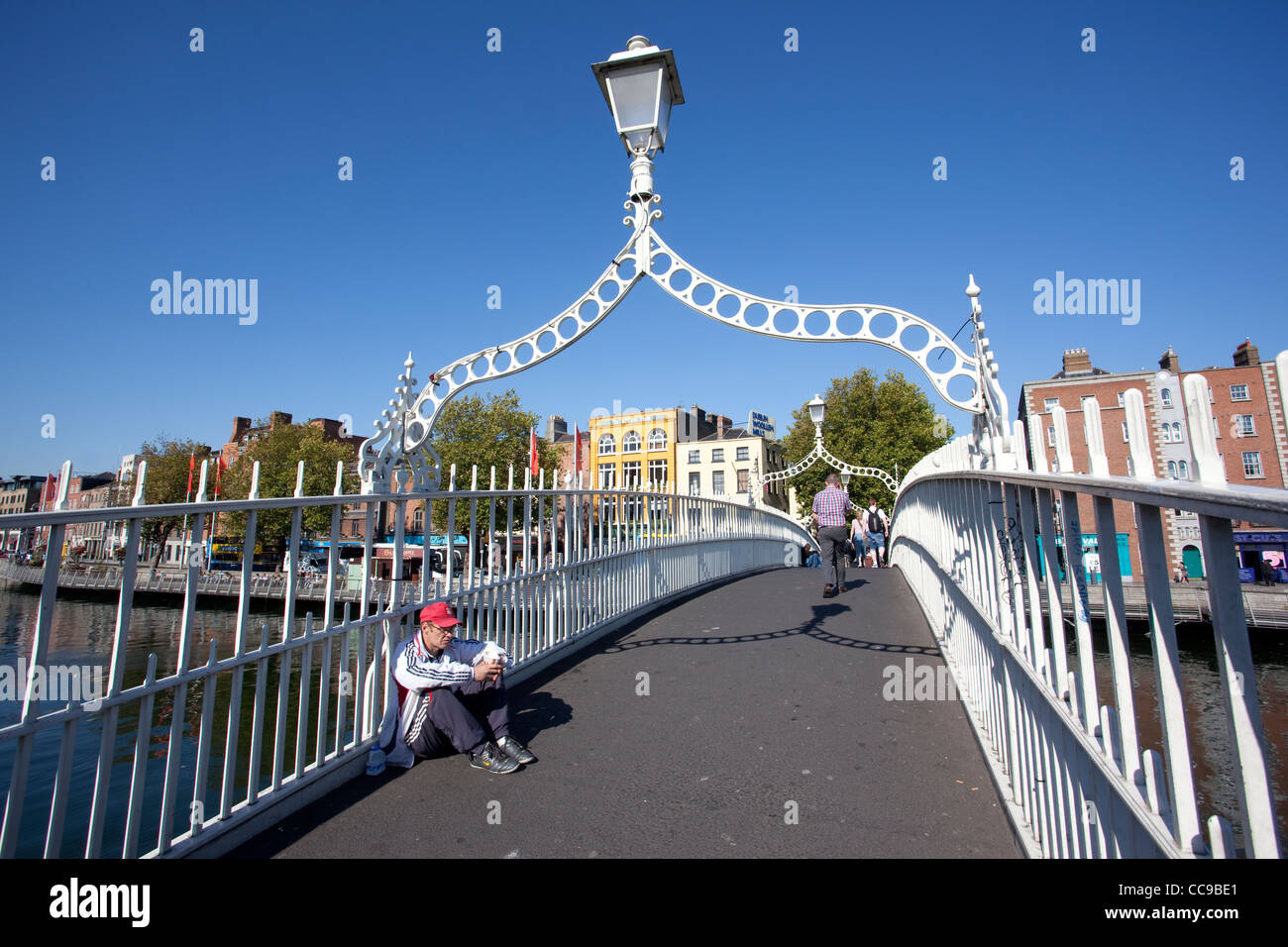 Ein Obdachloser sitzt auf Ha Penny Brücke über den Liffey-Fluss in Richtung untere Ormond Quay Central Dublin Irland. Stockfoto