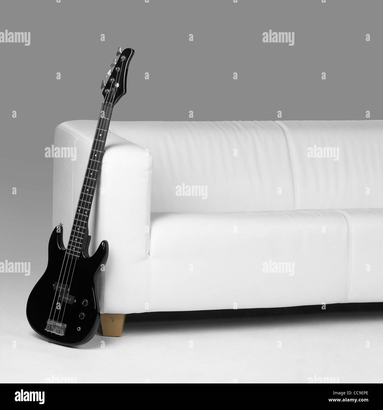 Black Bassgitarre an weißen Sofa in grau zurück lehnen Stockfoto