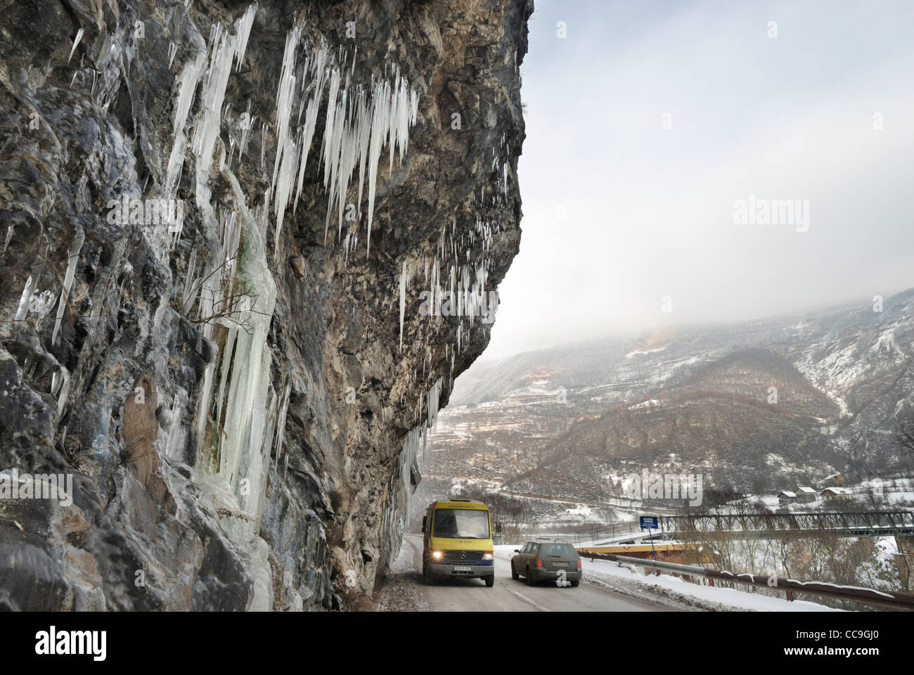 Fahrzeugen, auf einem gefrorenen Straße mit Eiszapfen wachsen im Winter auf einer überhängenden Felswand entlang dem Tal des Flusses Vrbas Bosnien und Stockfoto