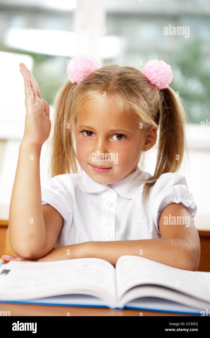 Porträt eines jungen Mädchens in der Schule an der Rezeption. Vertikale Schuss. Sitzen mit hob die Hand - sie weiß Antwort Stockfoto