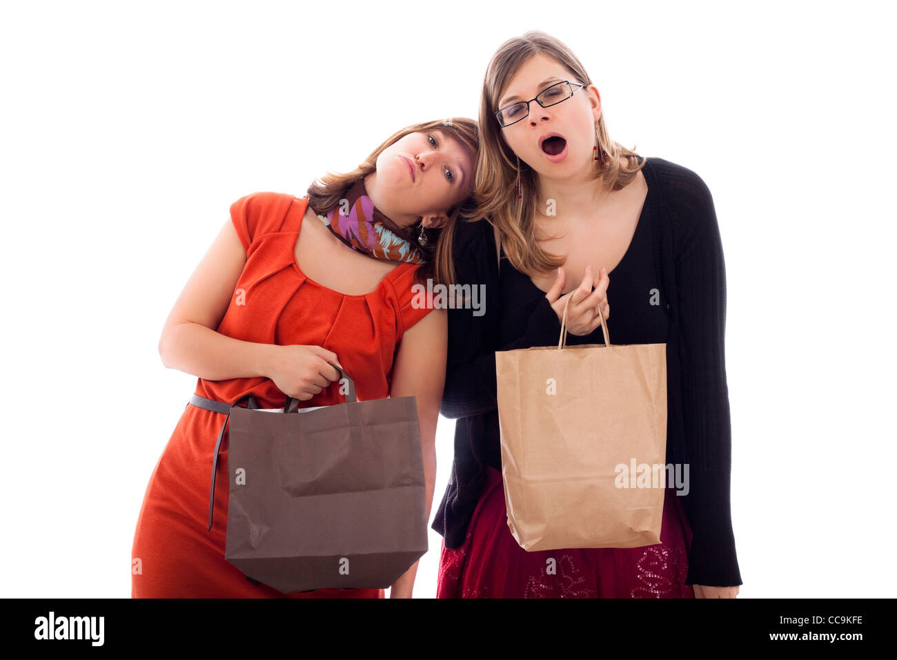 Zwei junge Frauen müde einkaufen, isoliert auf weißem Hintergrund. Stockfoto