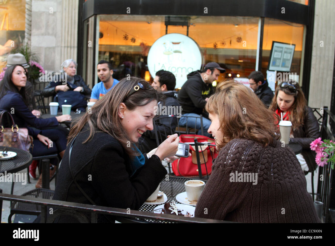 Zwei Frauen Lächeln betrachten eine smart-Handy in einem Straßencafé auf Newbury St., Boston, Mass. Oktober 2010. Stockfoto