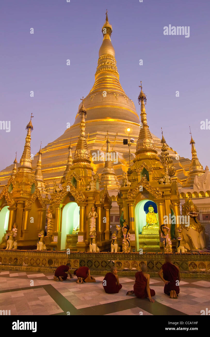 Neuling Mönche beten vor der Main-Stupa der Shwedagon Paya (Pagode) in der Dämmerung | Yangon (Rangoon) | Myanmar (Burma) Stockfoto