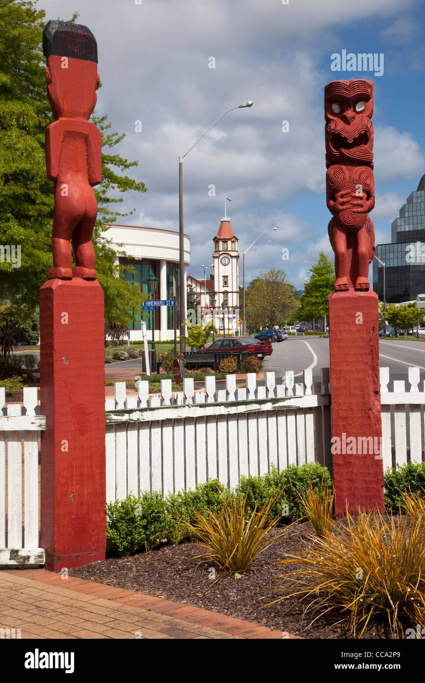Rotorua, Neuseeland. Maori Totems am Eingang zum Stadtpark. Stadt Uhrturm in Ferne. Stockfoto