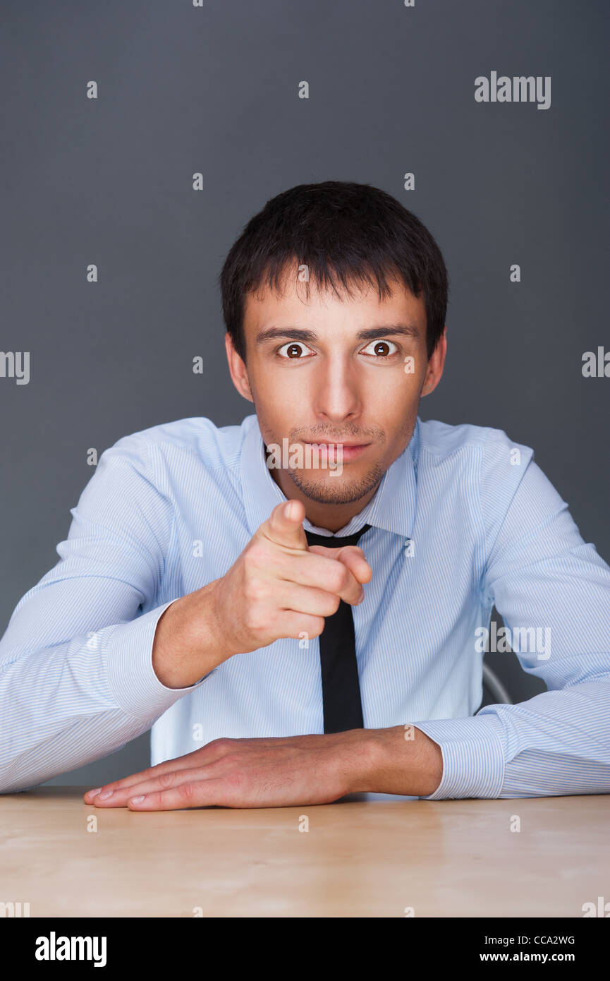 Porträt der Aconfident jungen Geschäftsmann im Anzug beim Sitzen in seinem Büro auf Sie gerichtet Stockfoto