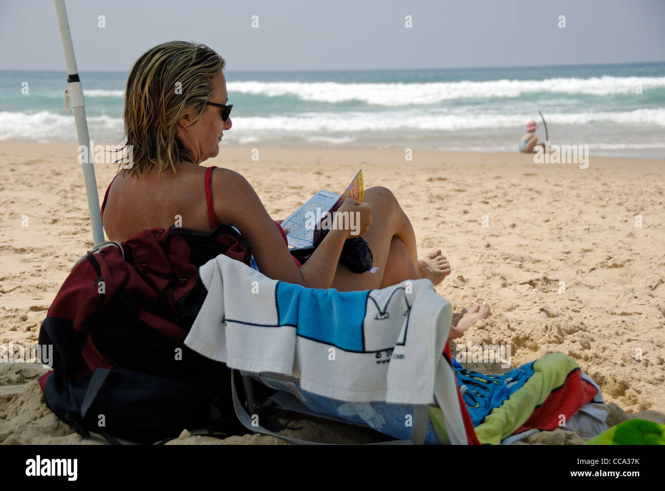 Frau macht Sudoku am Strand, Frankreich Stockfoto