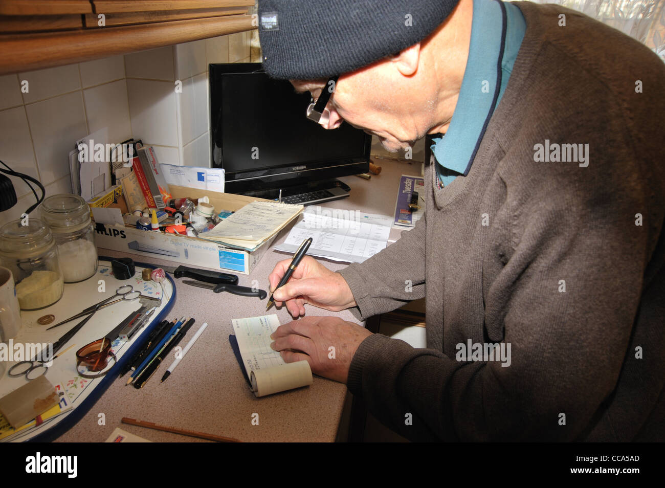 Ein älterer Mann einen Scheck schreibt. Stockfoto
