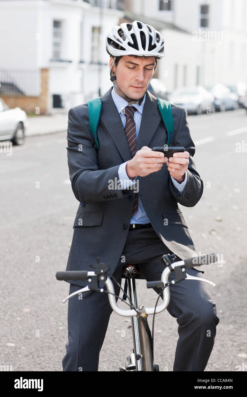 Mitte adult Geschäftsmann mit Handy, um Text auf dem Fahrrad Stockfoto