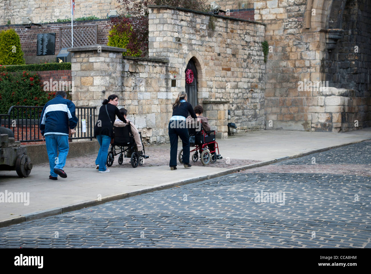 Zwei Personen Rollstuhl geschoben in Richtung East Gate von Lincoln Castle Stockfoto