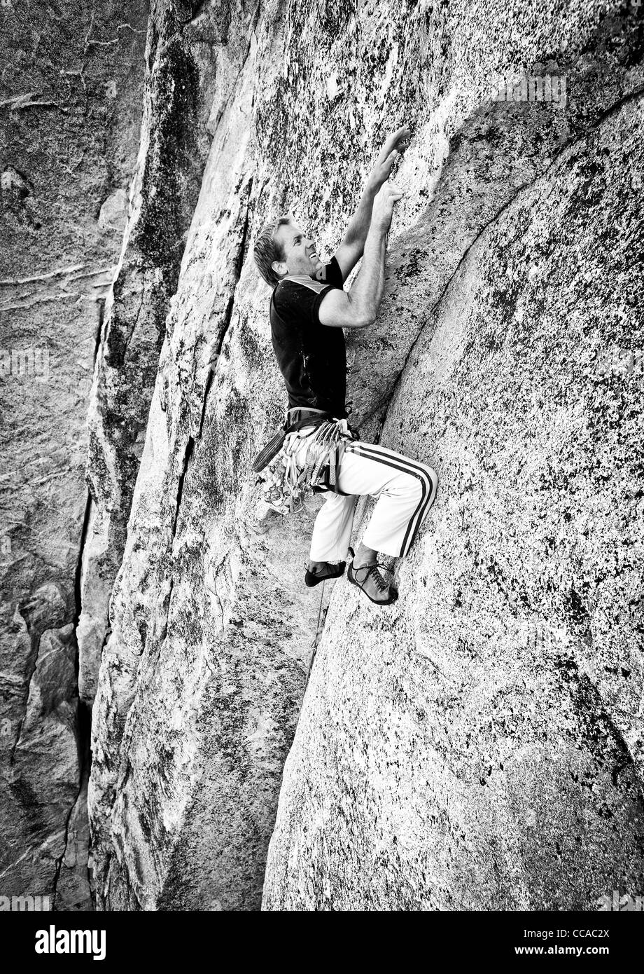 Männliche Kletterer kämpft für seinen nächsten Griff auf einem anspruchsvollen Aufstieg. Stockfoto