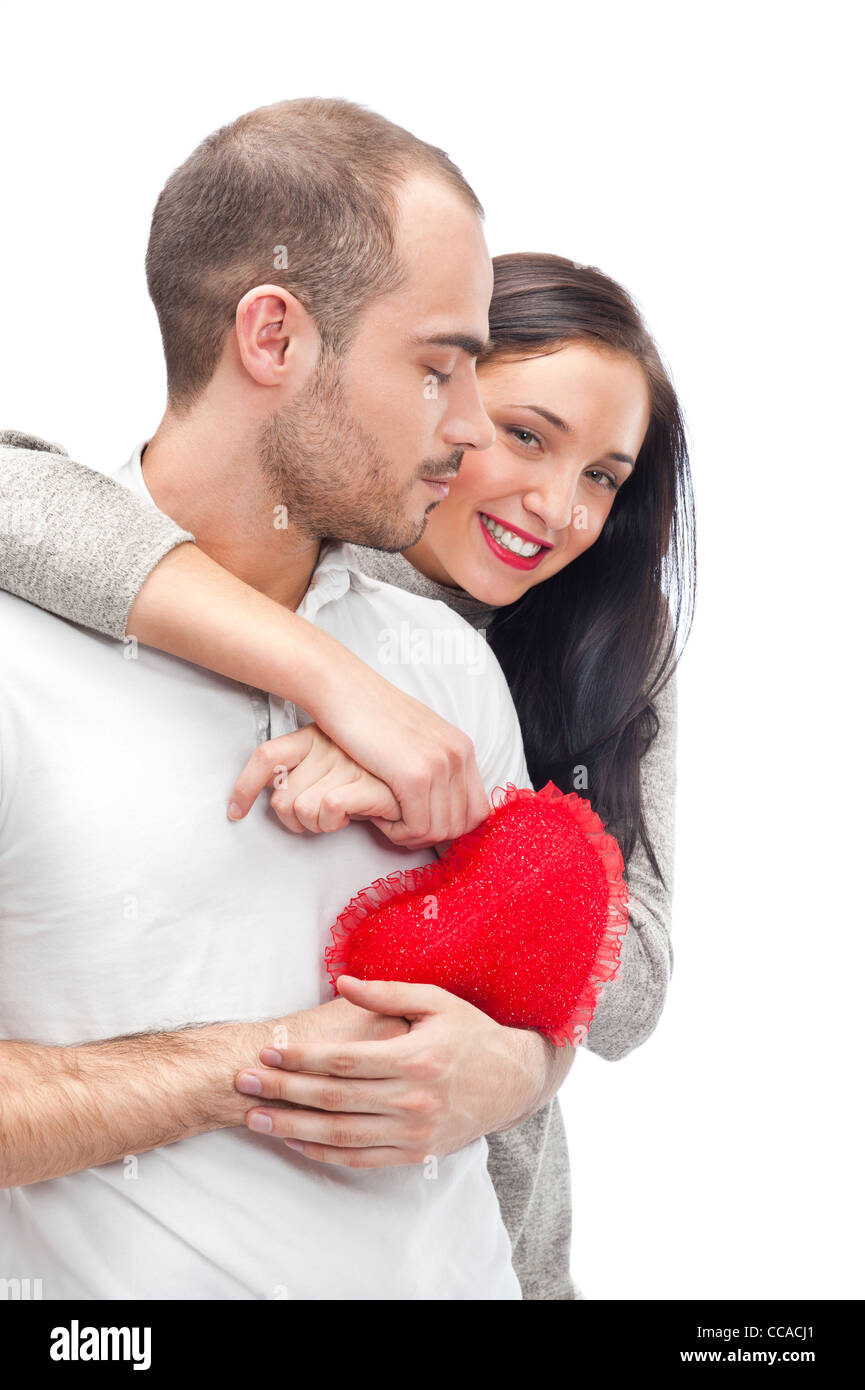 Junge Erwachsene Brautpaar mit roten Herz auf weißem Hintergrund, umarmen und lachen Stockfoto