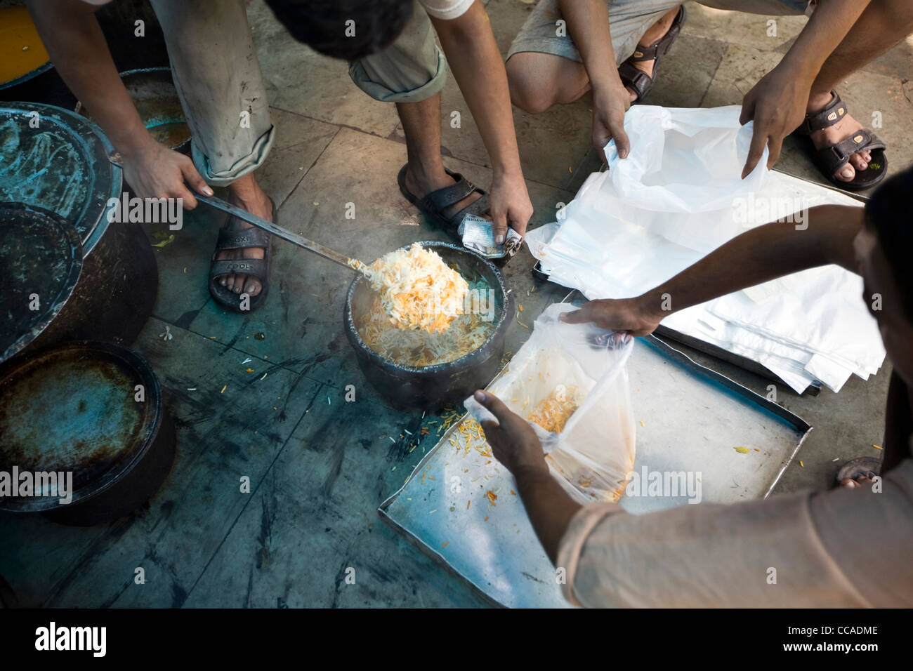 Männer Löffel Biryani in Plastiktüten für die Auslieferung am Babu Shahi Bawarchi, New Delhi, Indien Stockfoto