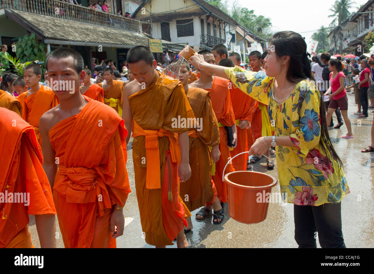 Buddhistische Mönche in einer Prozession mit Wasser geworfen über sie für einen Segen auf Mue Nau, den mittlere Tag der Lao Neujahr (Pi Mai Lao), Luang Prabang, Laos Stockfoto