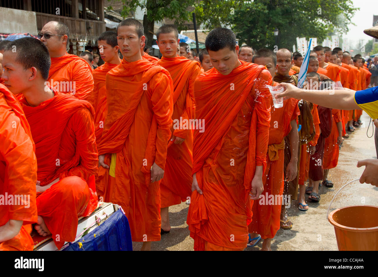 Buddhistische Mönche in einer Prozession mit Wasser geworfen über sie für einen Segen auf Mue Nau, den mittlere Tag der Lao Neujahr (Pi Mai Lao), Luang Prabang, Laos Stockfoto