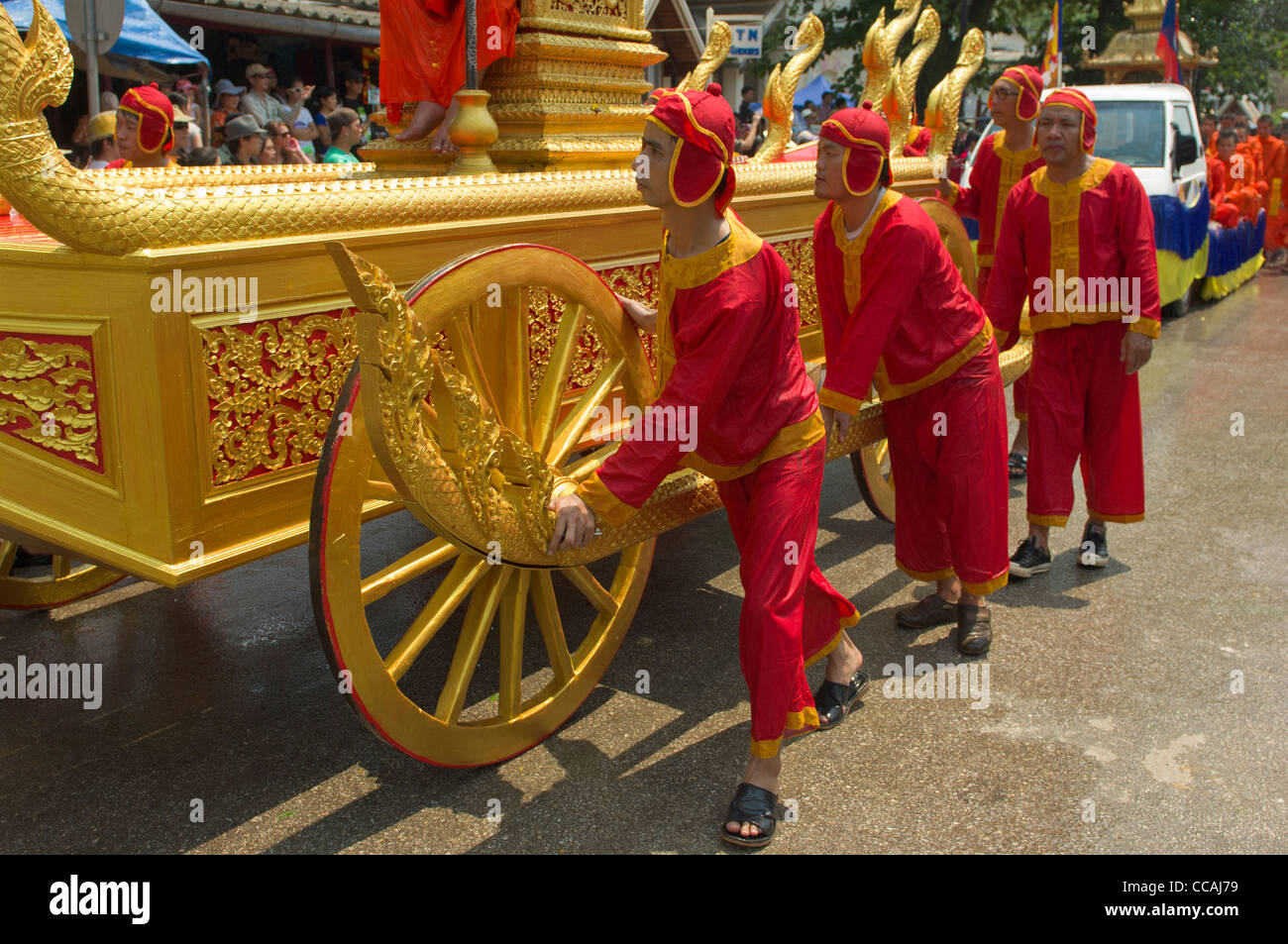 Ministranten, drücken Sie eine reich verzierte goldene Kutsche Prozession Mue Nau, Lao Neujahr (Pi Mai Lao), Luang Prabang, Laos Stockfoto