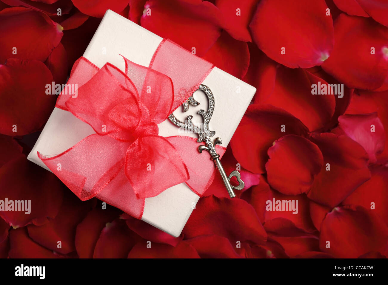 Valentines Geschenk-Box mit Schlüssel auf Rosenblättern Hintergrund Stockfoto