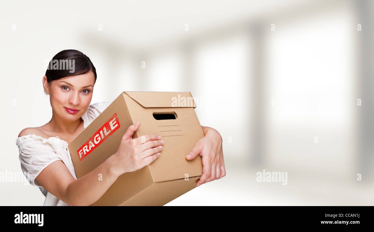 Lächelnde Frau in ihrem Haus hält Boxen. Sie ist Umzug in ihrem neuen Zuhause. Hypothek-Konzept Stockfoto