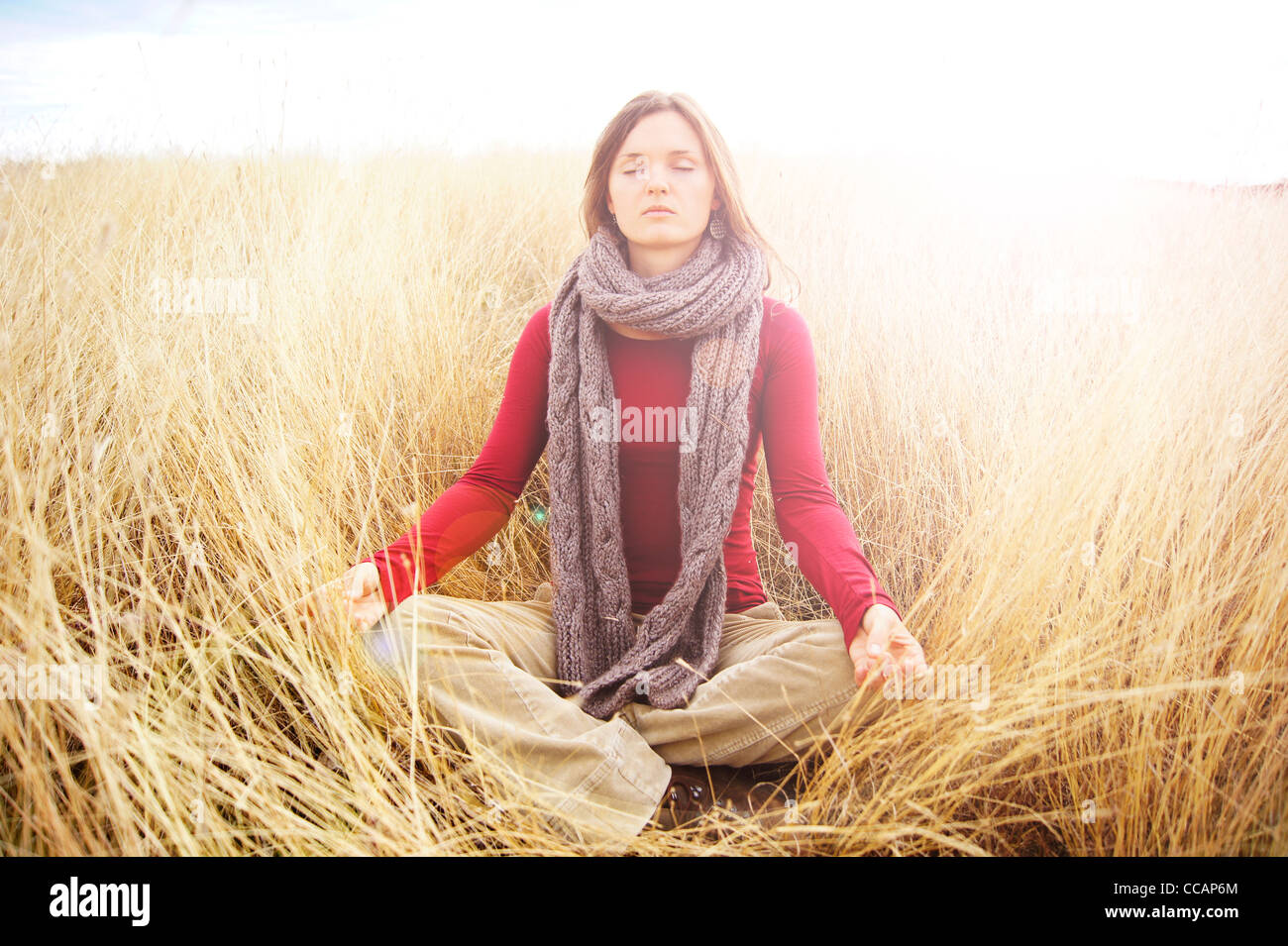 Schöne junge Frau, die in strahlendem Licht in eine lange Wiese Ruhe meditieren Stockfoto
