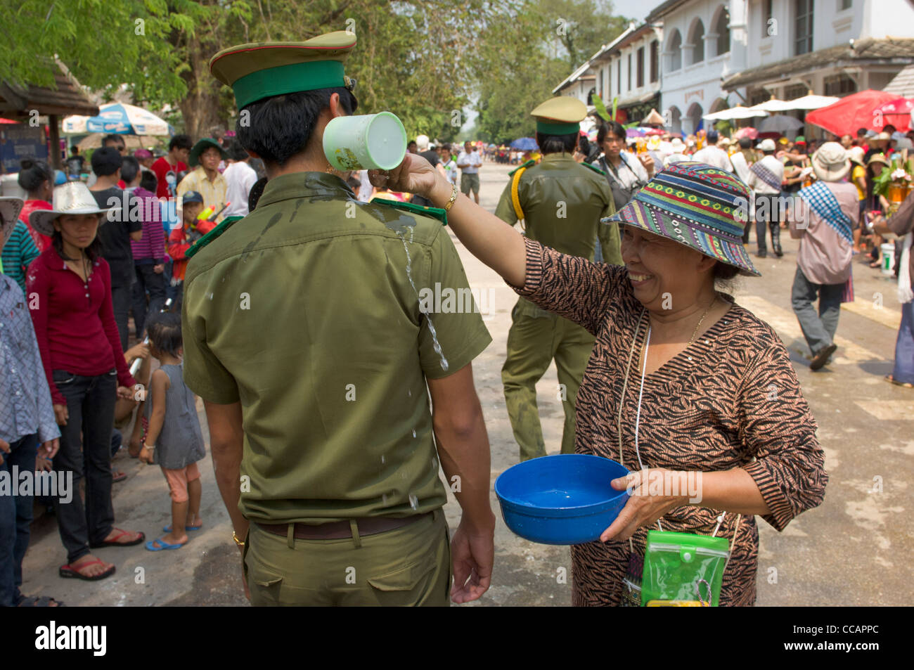 Freudiger Lao Frau gießt Wasser auf einen Polizisten als Segen, Lao Neujahr (Pi Mai Lao), Luang Prabang, Laos Stockfoto