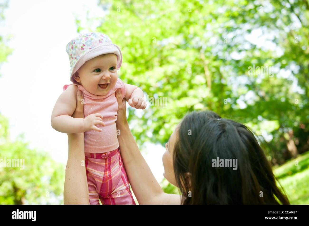 Glückliche Mutter heben ihr schönes Kind draußen im park Stockfoto
