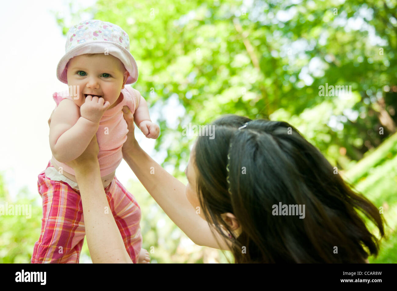 Glückliche Mutter heben ihr schönes Kind draußen im park Stockfoto
