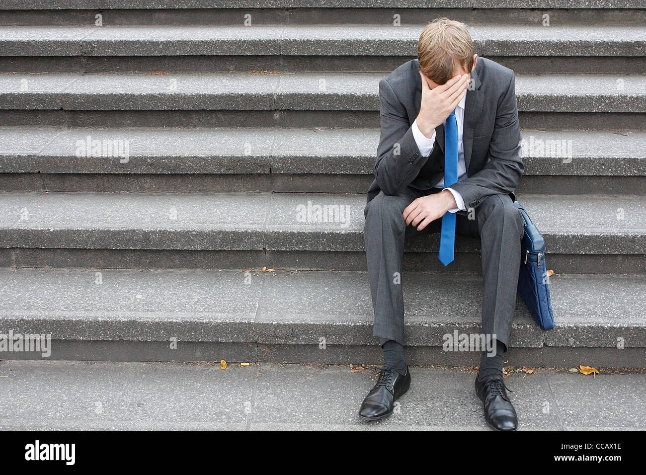 Ein besorgt Business-Mann sitzt auf einer Treppe Stockfoto