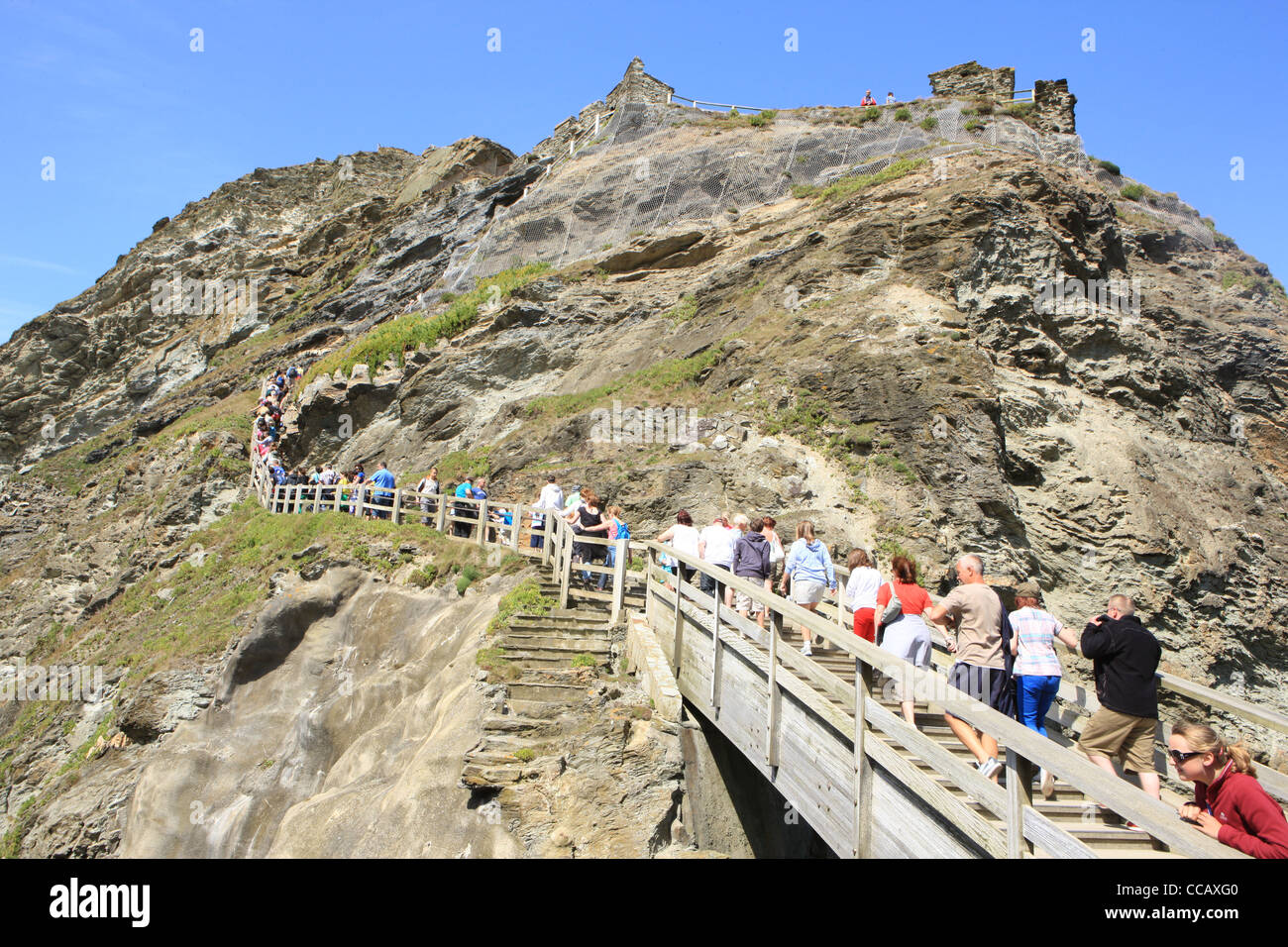 Besucher an der North Cornish Küste in Tintagel an einem Sommertag, Klettern auf den Klippen zu König Arthurs Castle Stockfoto