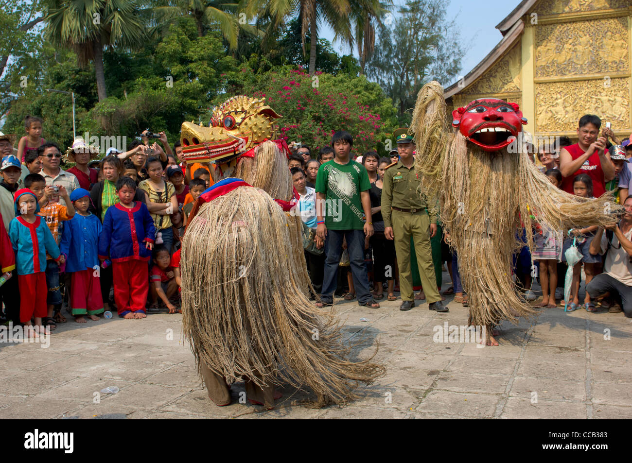 Maskierte Fabelwesen Singkaeo-Singkham und Pou Nyer tanzen vor der goldenen Sim an Wat Xieng Thong auf Mue Nau, des mittlere Tages der Lao Neujahr (Pi Mai Lao), Luang Prabang, Laos Stockfoto
