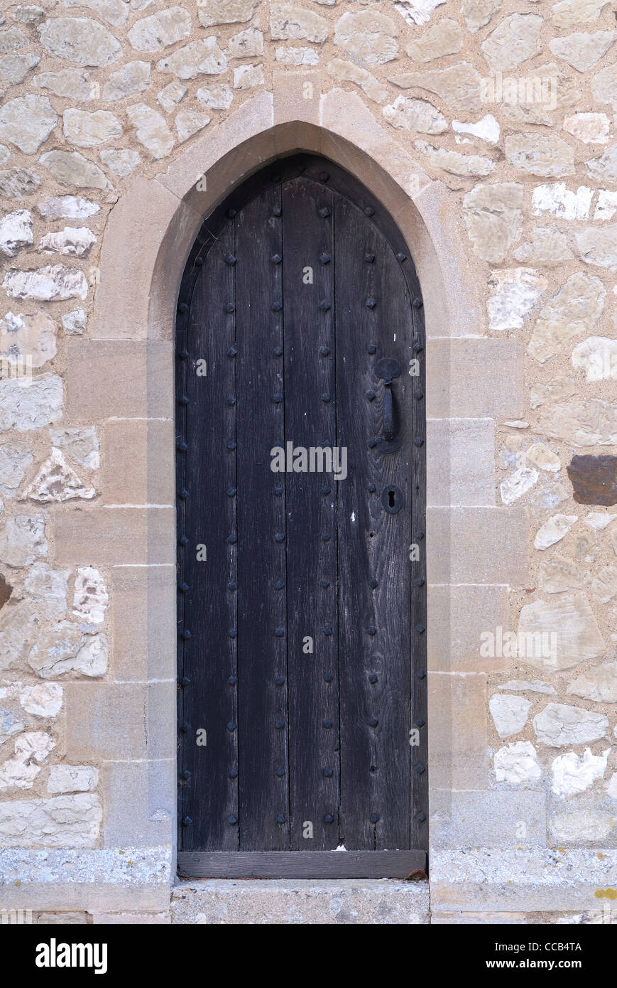 Schwarzen mittelalterlichen Kirchentür von Stein umgeben. Stockfoto
