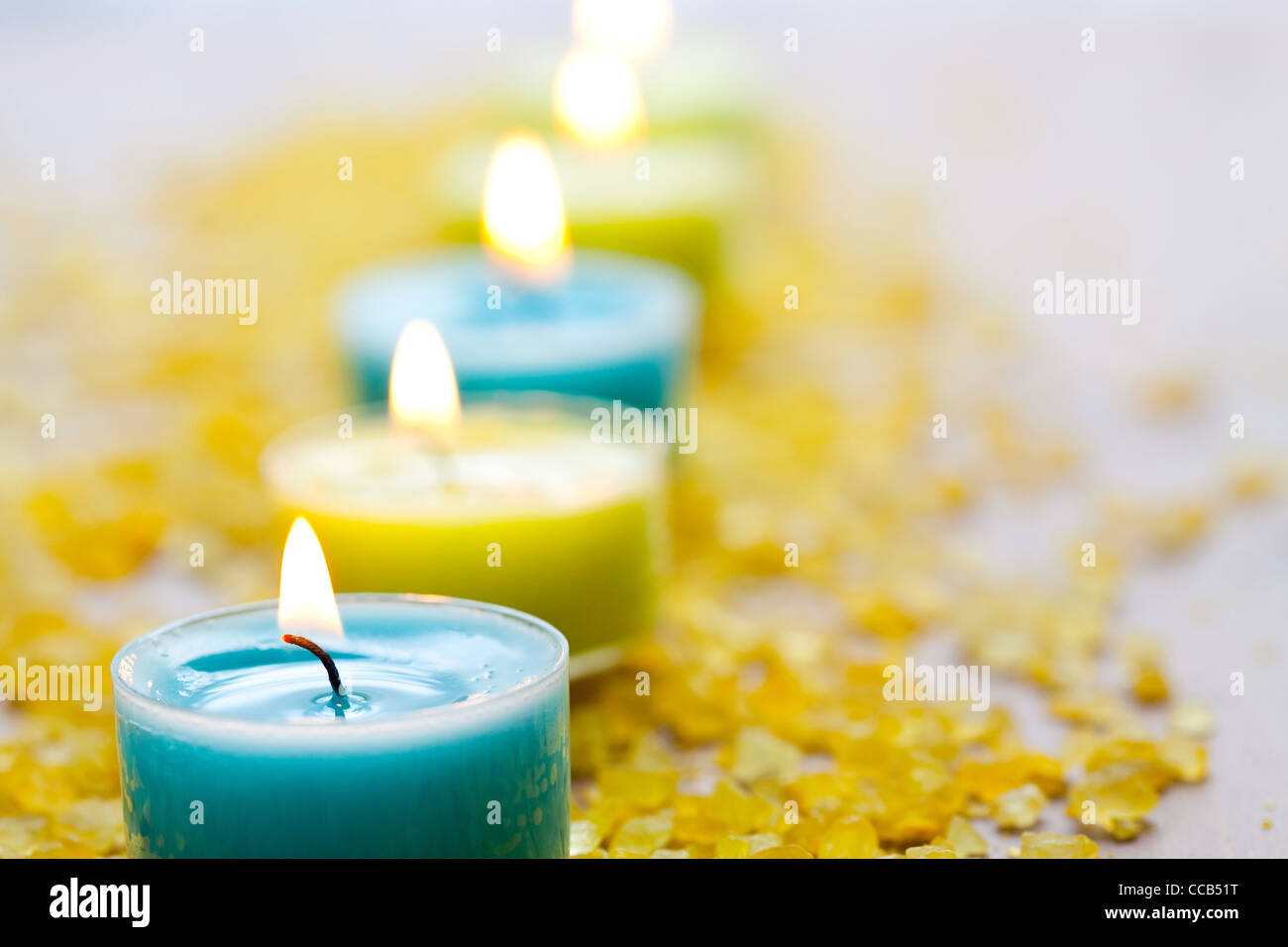 Nahaufnahme der blauen und gelben Kerzen mit gelben Badesalz Stockfoto