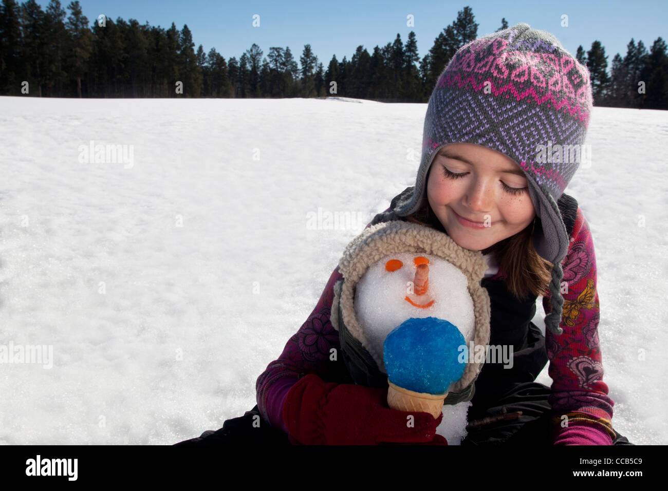 Mädchen machen einen Schneemann an einem sonnigen Wintertag. Stockfoto