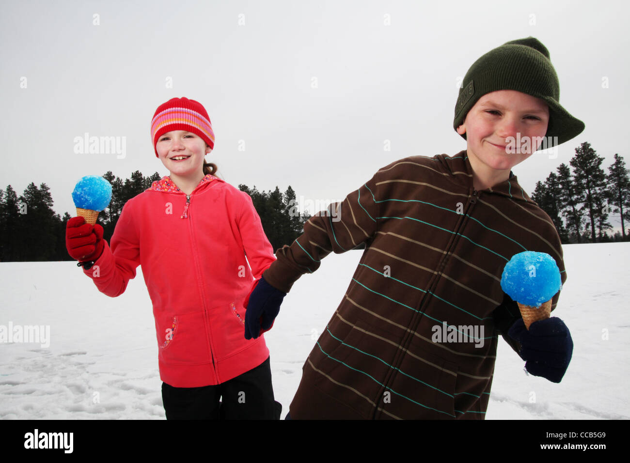 Zwei Kinder essen Schnee Kegel an einem Wintertag Stockfoto