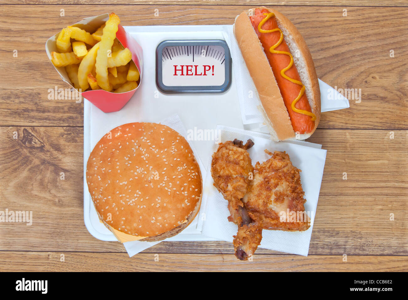 Verschiedene Arten von Junk-Food wie Brathähnchen und einen Hot Dog auf Waagen Stockfoto