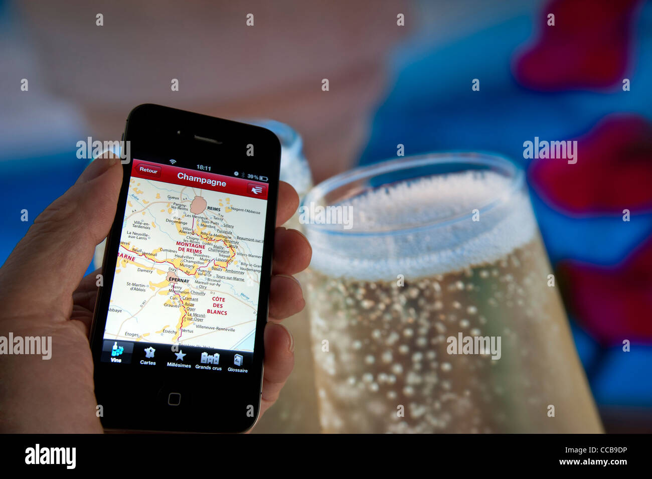 Hand, die Apple iPhone 4 s mit Bildschirm Sektherstellung Regionen mit Champagner Gläser hinter Reims Frankreich Stockfoto