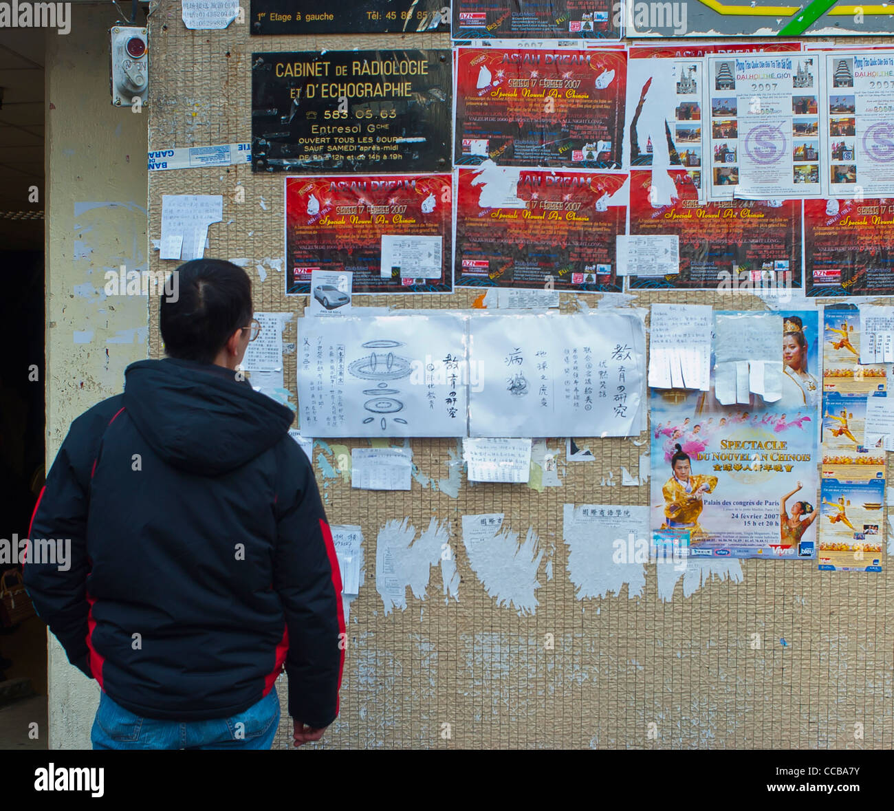 Paris, Frankreich, Young Chinese man Reading Jobs Board kündigt an der Wand vor dem Asian Store an, auf Straßenplakaten in Chinatown, District, an der Wand Stockfoto