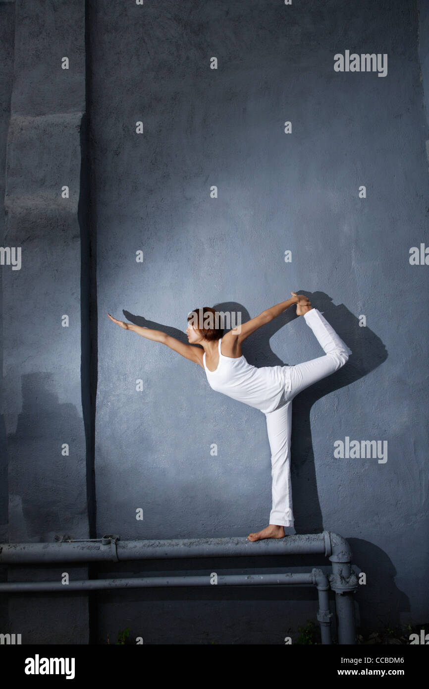 junge Frau beim Yoga auf ein Rohr vor Wand stehend Stockfoto