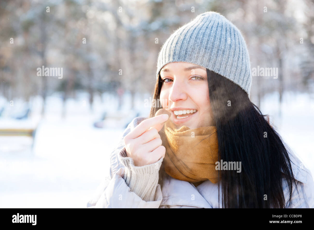 Porträt von jungen schönen Mädchen essen leckere Pralinen und Spaß im Freien im Winterwald Stockfoto