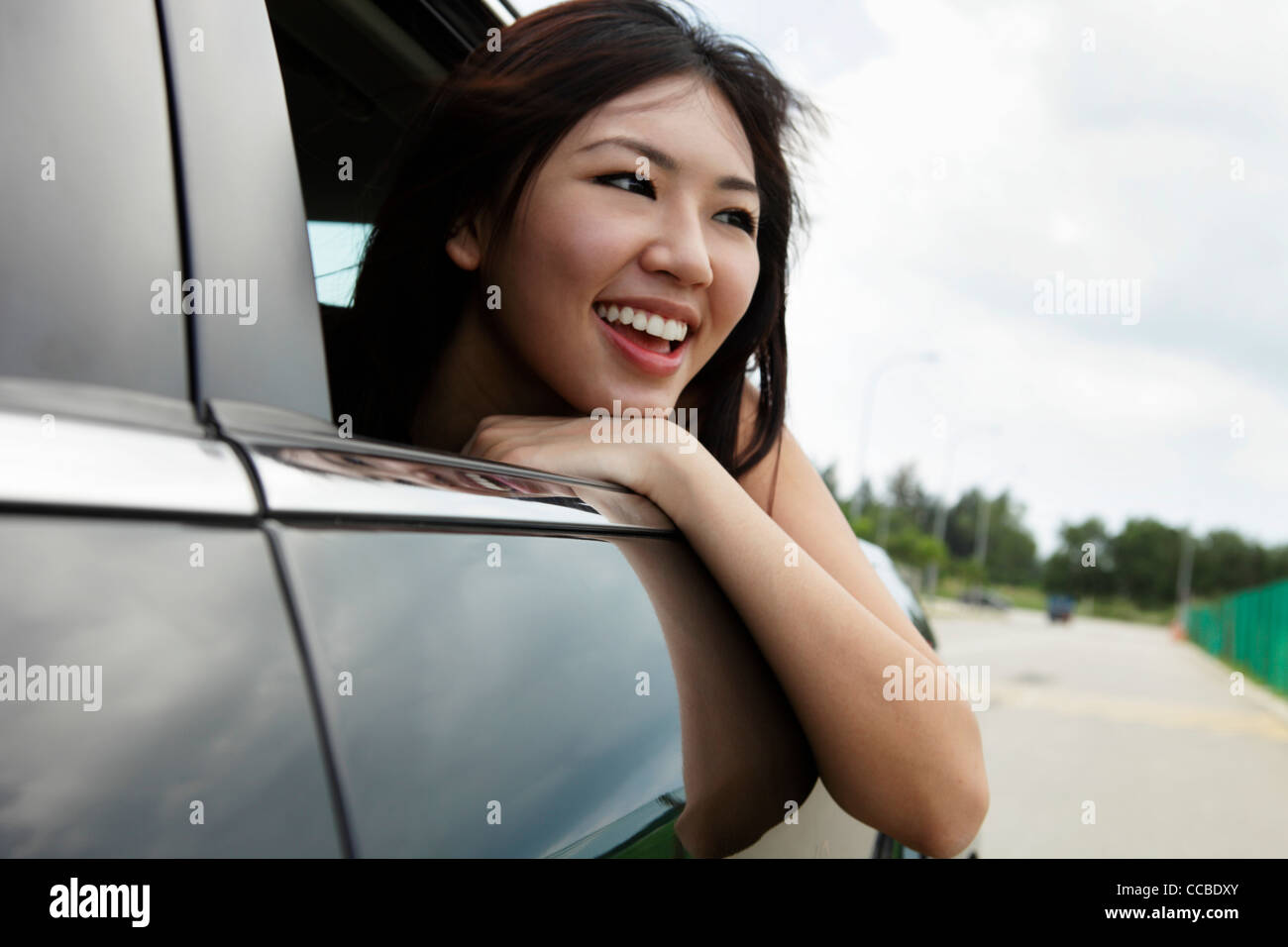 Junge Frau mit Kopf aus dem Auto Fenster lachen Stockfoto