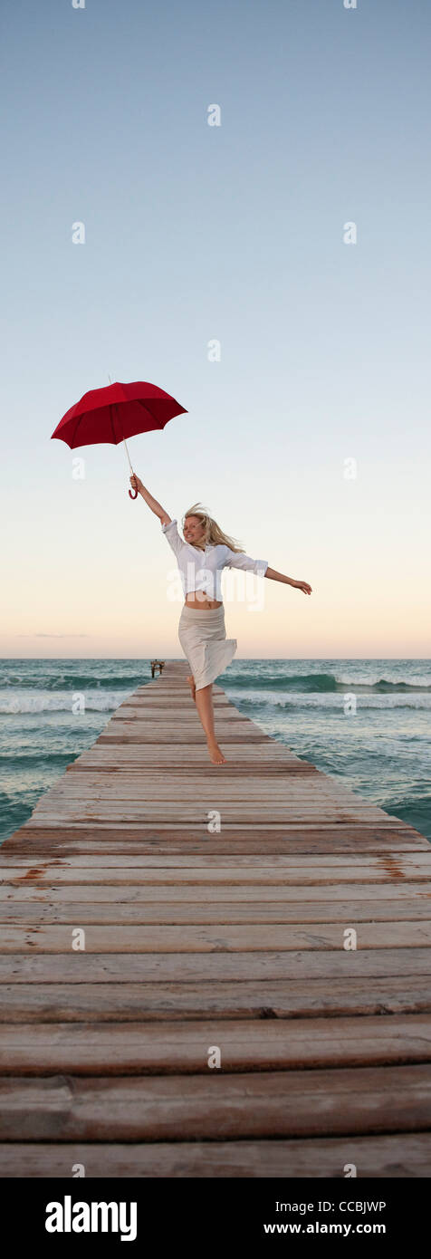 Junge Frau am Pier halten Dach springen Stockfoto