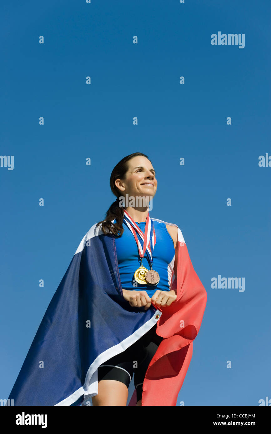 Sportlerin auf Siegertreppchen, eingehüllt in französische Flagge Stockfoto