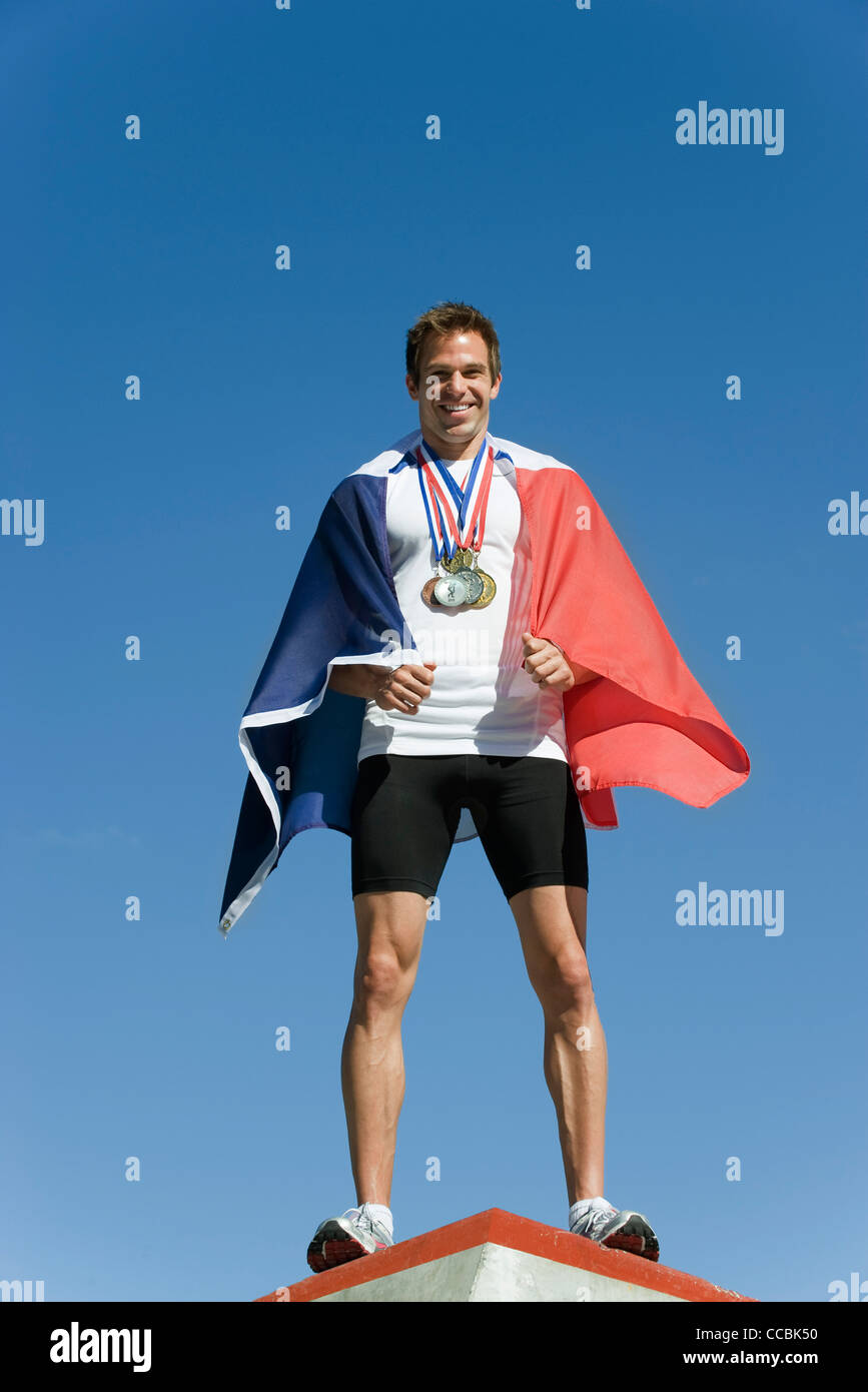 Männliche Sportler geehrt auf Podest, eingehüllt in französische Flagge Stockfoto