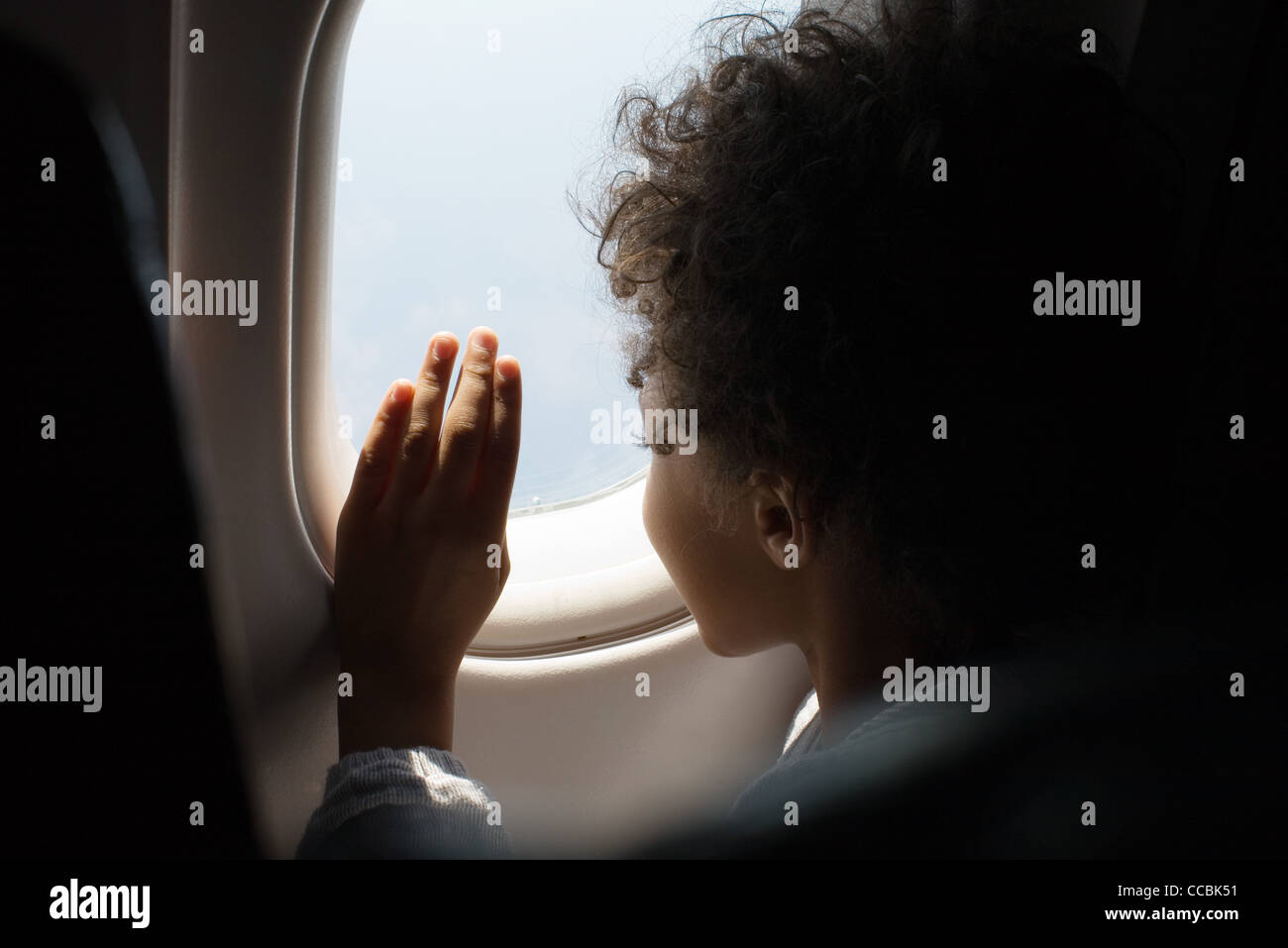 Junge schaut aus Flugzeugfenster Stockfoto