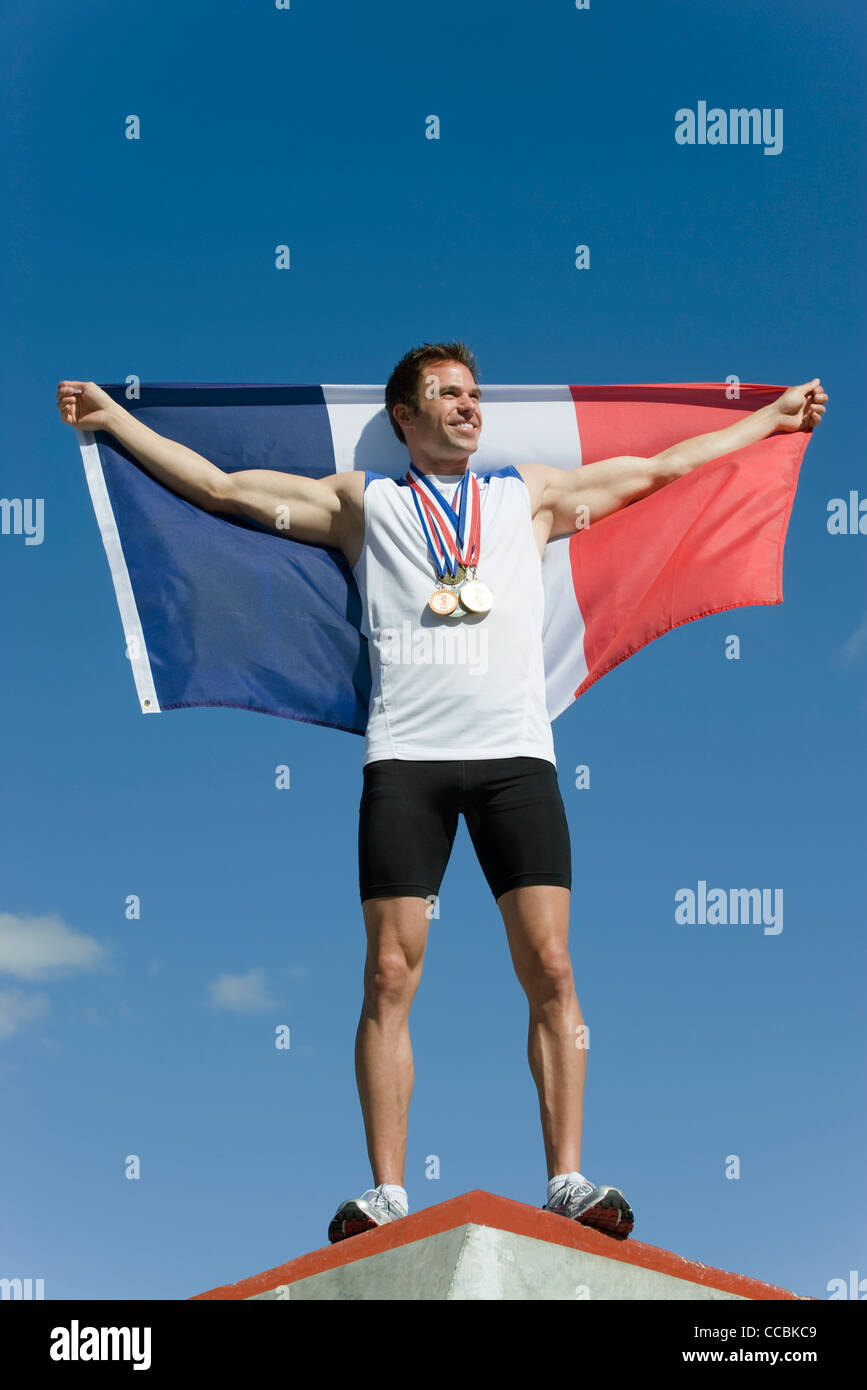 Männliche Sportler geehrt auf Podest, französische Fahne hochhalten Stockfoto