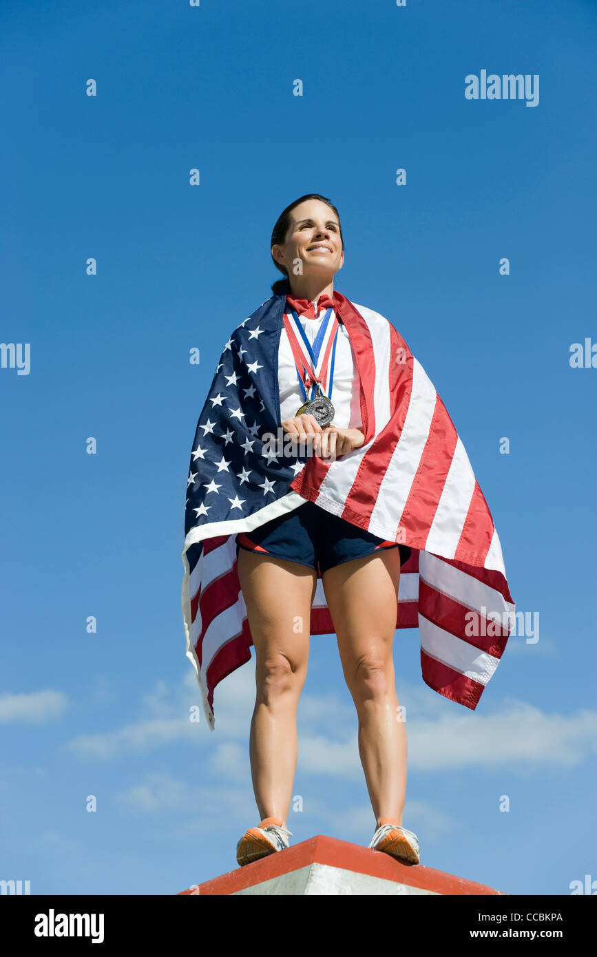 Weibliche Athleten geehrt auf Podest, eingehüllt in amerikanische Flagge Stockfoto