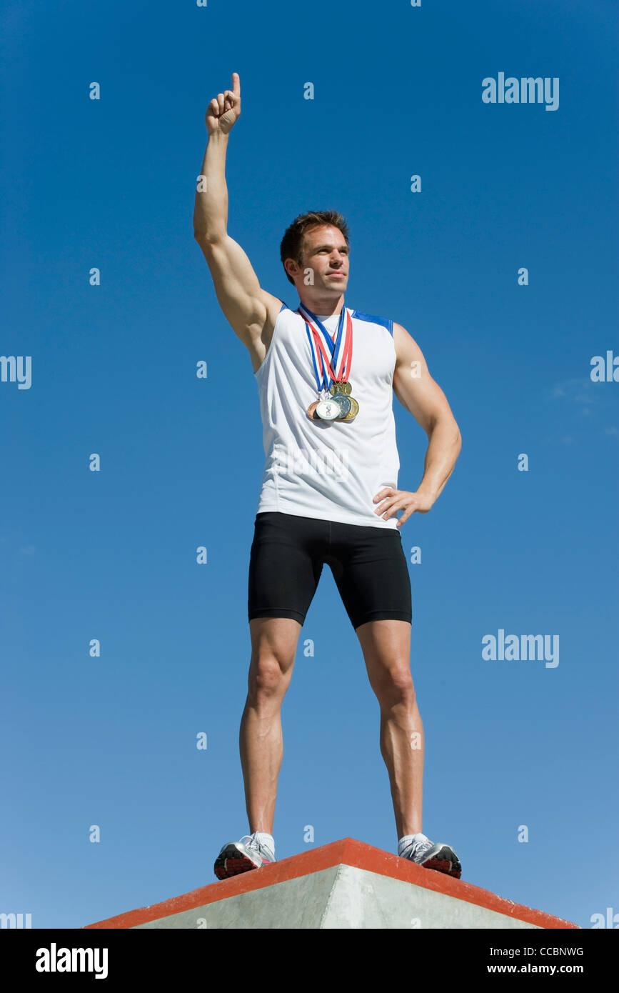 Männliche Athleten stehen auf Siegertreppchen mit Hand Sieg Stockfoto
