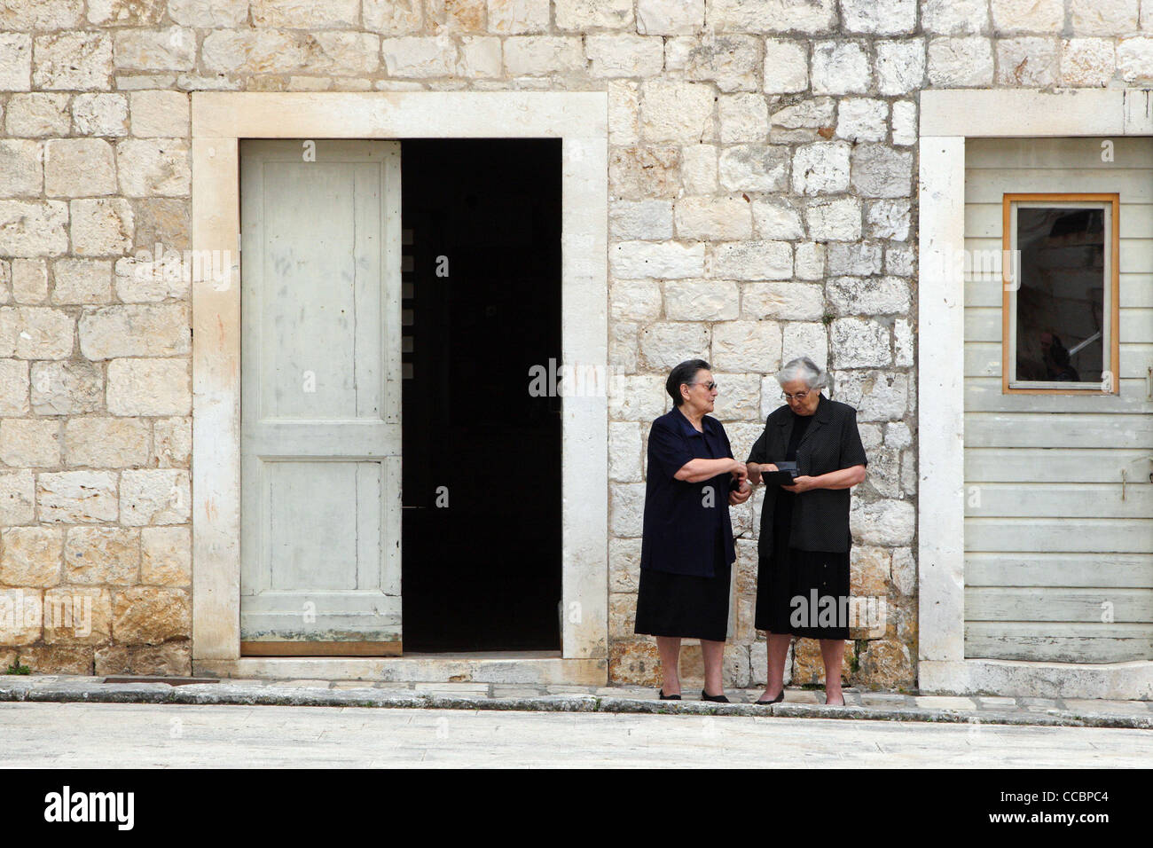 Zwei ältere Frauen Chat außerhalb ihrer Häuser in Hvar Kroatien. Stockfoto