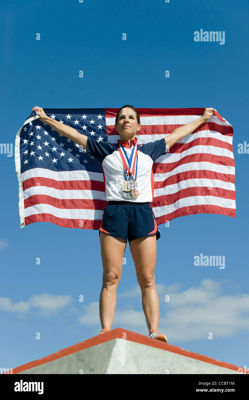 Weiblichen Athleten geehrt auf Podest, amerikanische Fahne hochhalten Stockfoto
